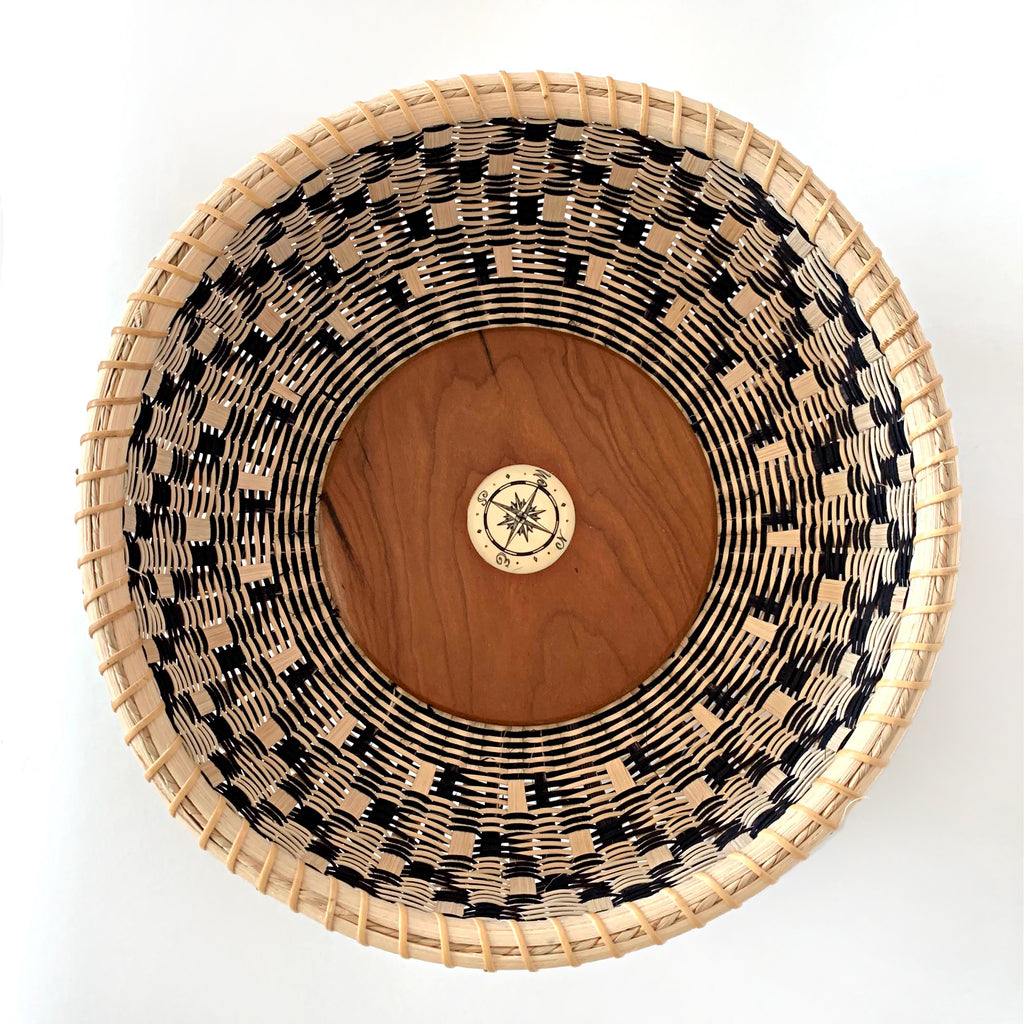 Round basket with natural and black pattern and cherry wood bottom with compass in the center by Susan Tyler at Cottage Curator - Sperryville VA Art Gallery